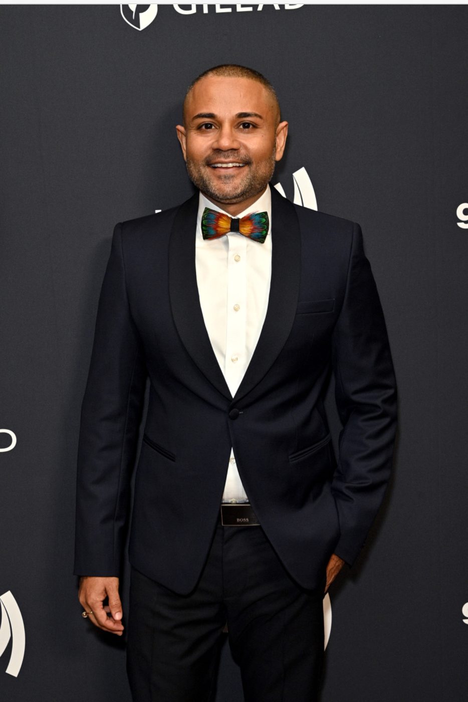 Shameek in a tuxedo and feather bow tie at a GLAAD event