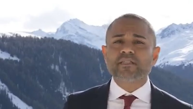 Shameek speaking on camera in Davos with snow-covered mountains behind him